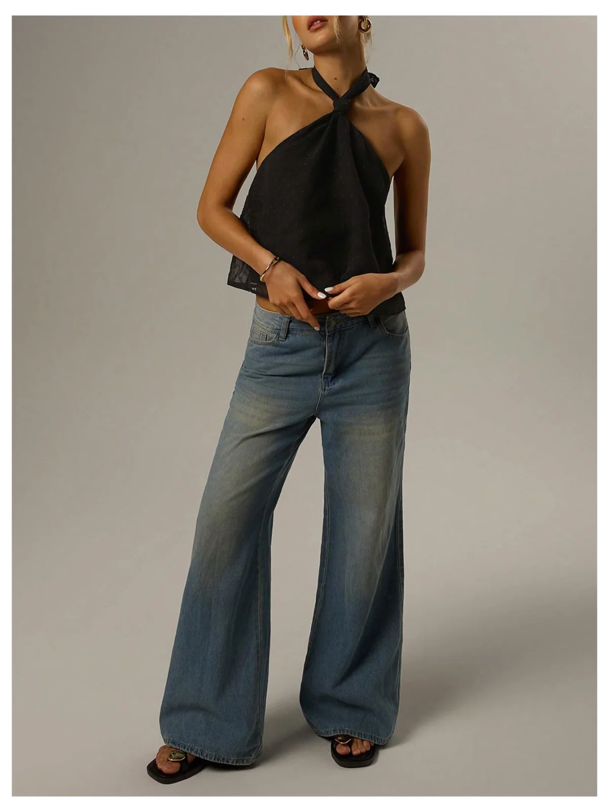 The tie-back Swiss-dot halter top in black, worn with wide-leg jeans